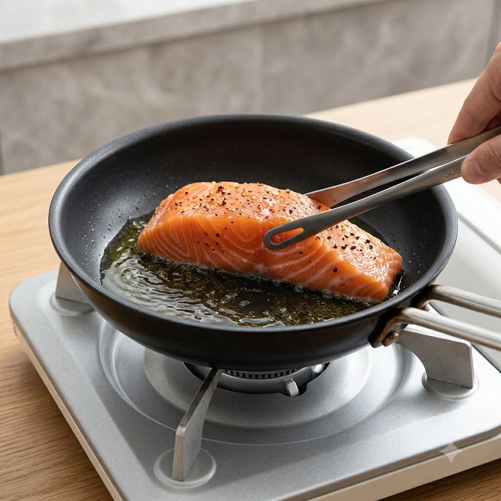 Un filetto di salmone fresco posizionato dal lato della pelle in una padella calda con lausilio di pinze da cucina.