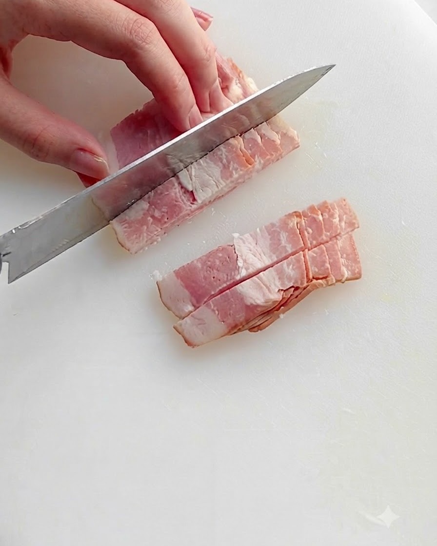 Pezzi di pancetta tritata che soffriggono in una padella calda con olio, mostrando grasso sfrigolante e bordi dorati.