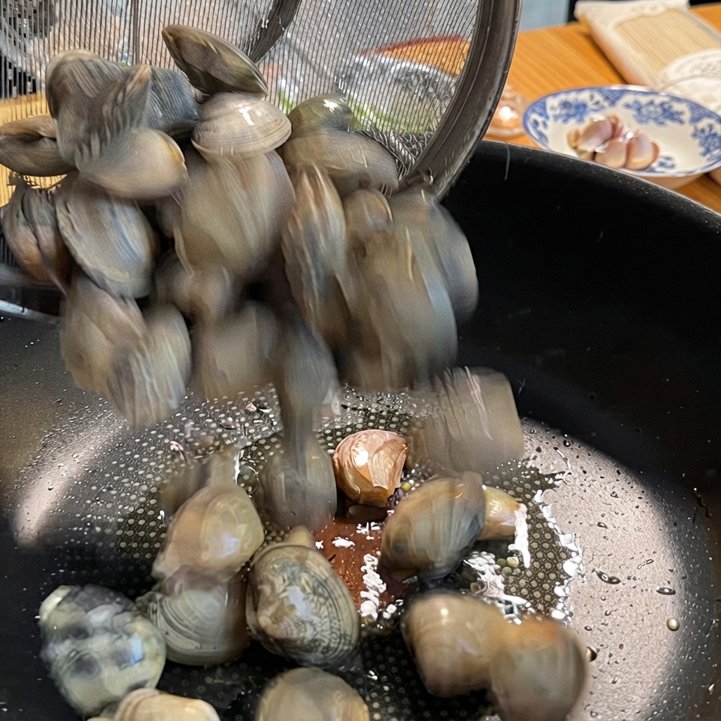 Vongole versate da un colino di metallo in una padella con laglio.