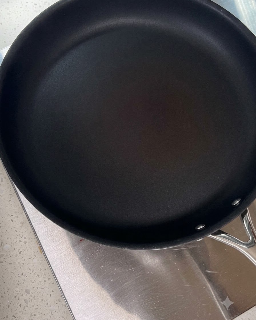 Una padella nera pulita che si scalda su un piano cottura.