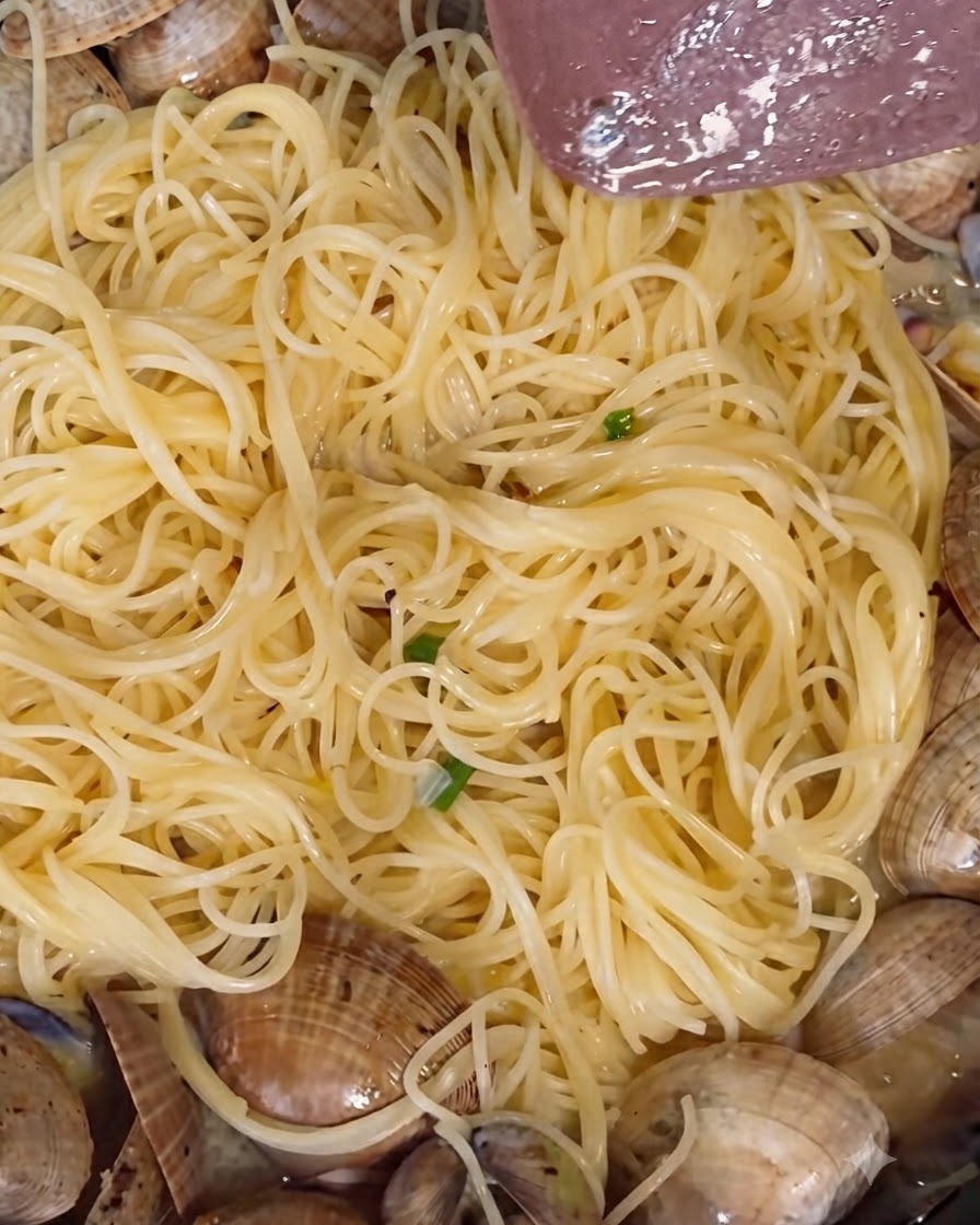 Polvere di pepe bianco e pepe nero macinato fresco cosparsi sulle vongole in cottura in una padella.