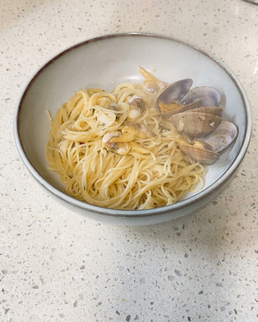 Piccoli pezzi di burro freddo inseriti in una padella contenente vongole cotte e brodo.