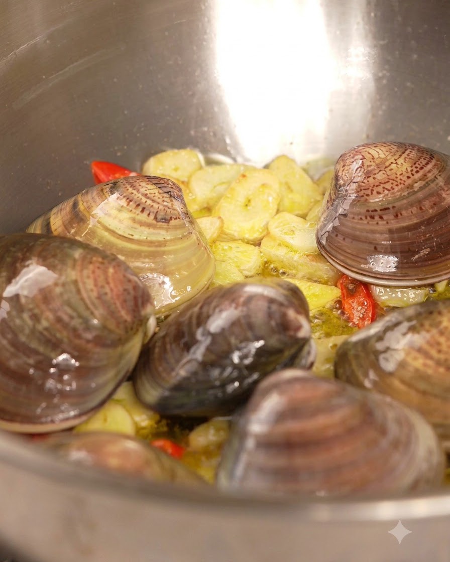 Vino bianco versato da una bottiglia allinterno di una padella con vongole, aglio e peperoncino.
