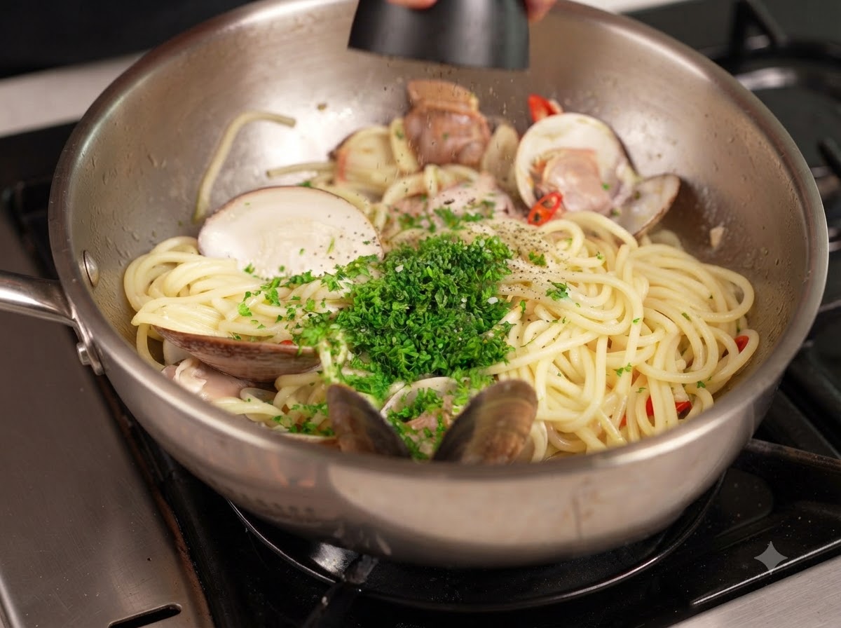 Pepe nero macinato da un mulinello sopra una padella di pasta e vongole guarnita con prezzemolo verde tritato.