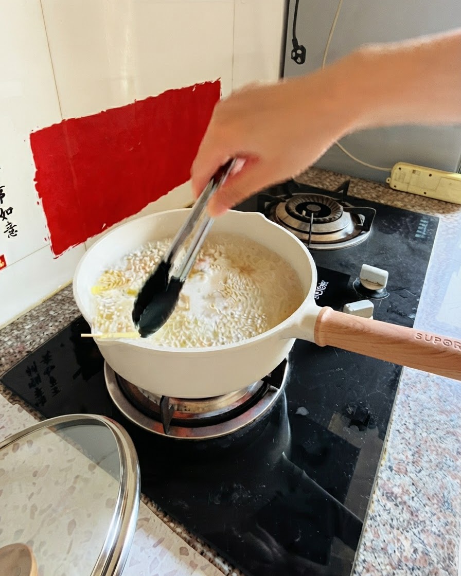 Pinze che mescolano la pasta in una pentola di acqua bollente sul fuoco.