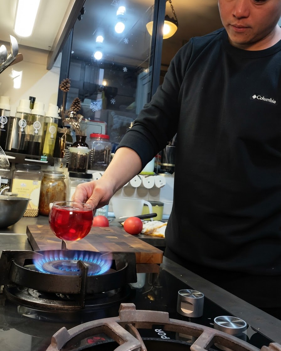 Un pomodoro tenuto sopra la fiamma blu di un fornello a gas con un taglio a croce sulla superficie.