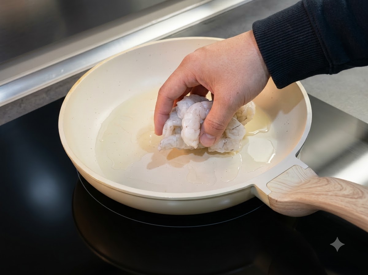 Gamberi scongelati disposti in una padella oliata per cuocere.