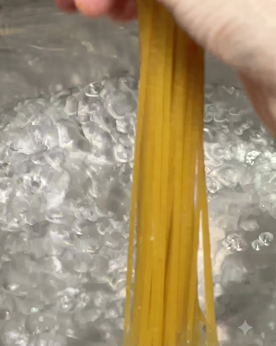 Spaghetti calati in una grande pentola di acqua bollente.