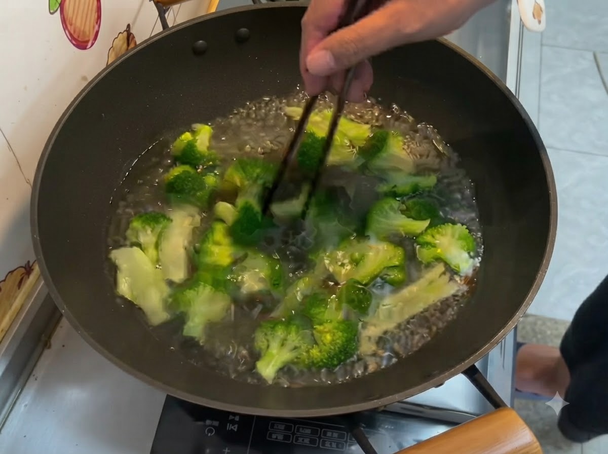 Cimette di broccoli verde brillante che bollono nellacqua allinterno di un wok, mescolate con le bacchette.