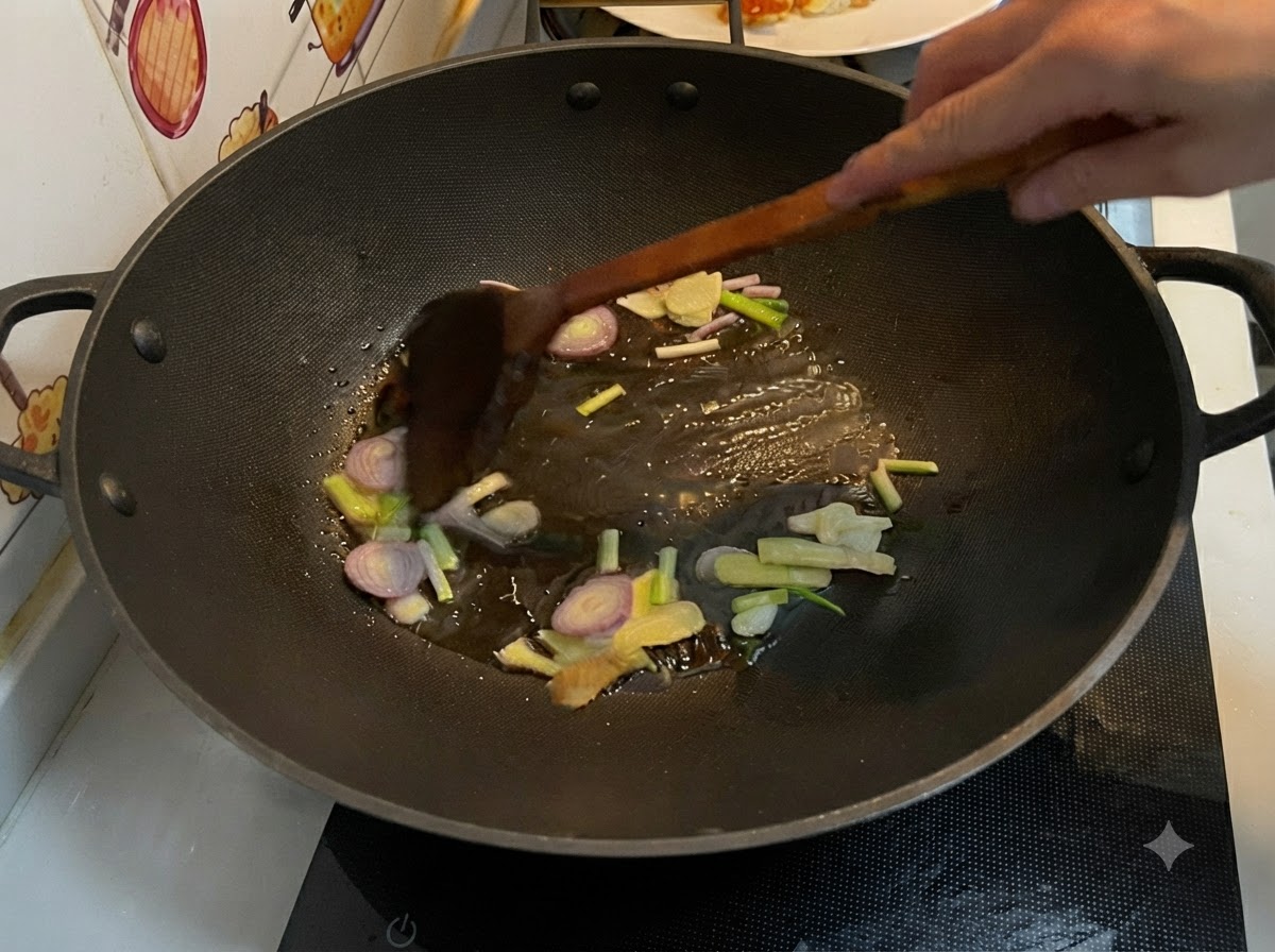 Zenzero affettato, aglio, scalogno e cipollotti che friggono in olio caldo dentro un wok, mescolati con una spatola di legno.