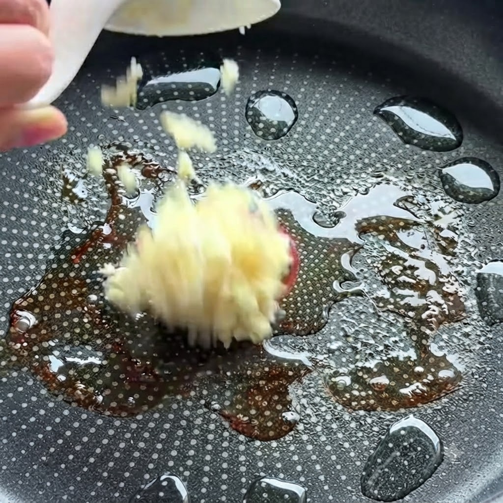 Aglio tritato aggiunto in una padella calda con olio.