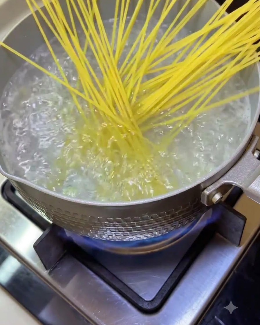 Spaghetti immersi in una pentola di acqua bollente e frizzante sul fuoco.