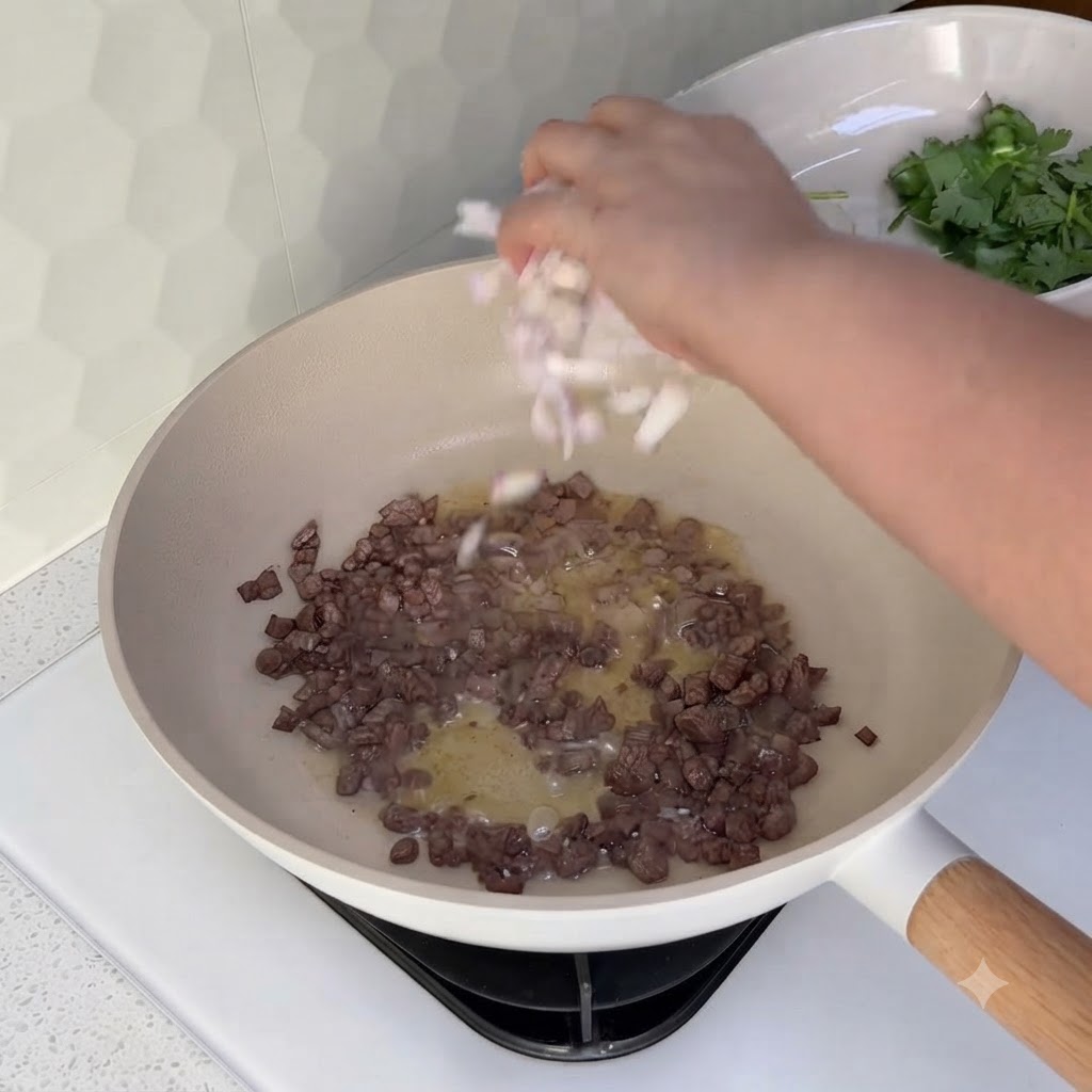 Cipolle a dadini cosparse in un wok contenente la carne macinata cotta.