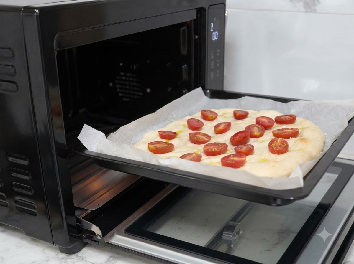 Una teglia da forno con limpasto della pizza condito che viene infilata in un forno nero.