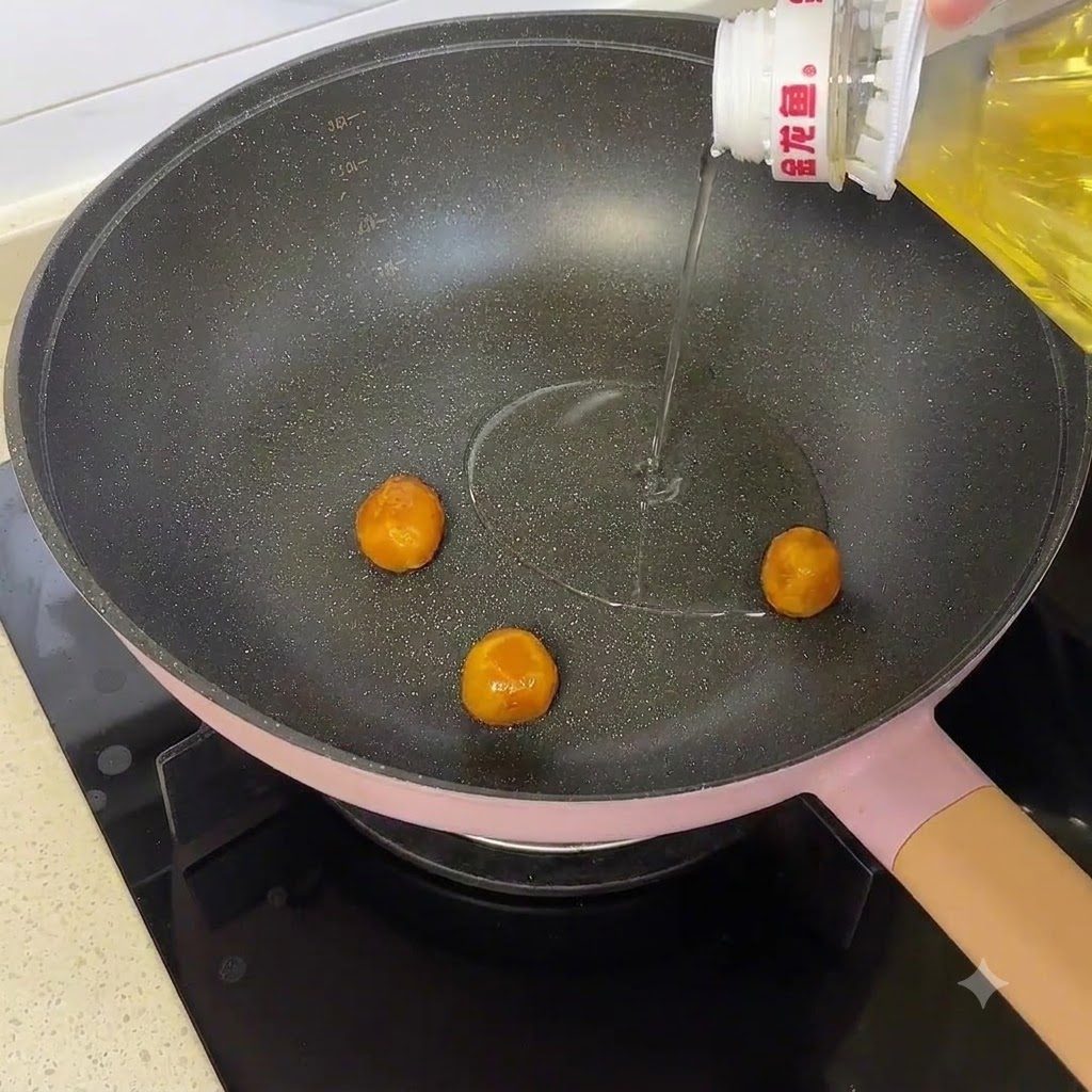 Tuorli duovo salati che cuociono in una padella mentre si aggiunge un filo dolio da una bottiglia.