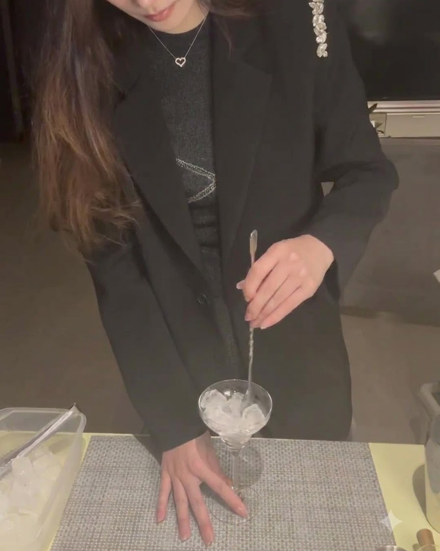 Cubetti di ghiaccio allinterno di una coppetta Martini mescolati con un cucchiaio da cocktail per raffreddarla.