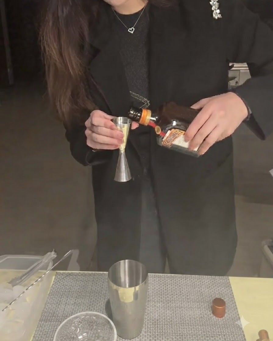 Cointreau versato in un jigger con un bricco dello shaker sottostante.