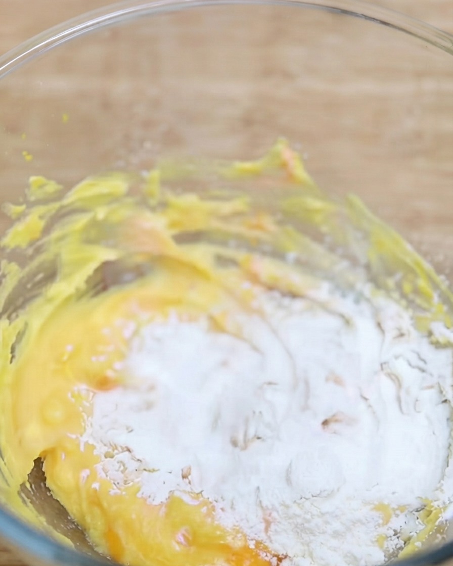 Polvere di matcha setacciata in una ciotola contenente la base di pasta gialla.