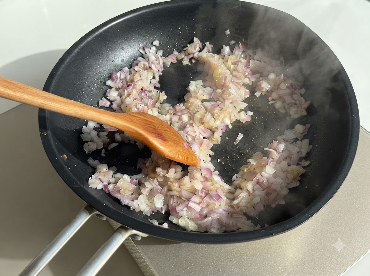 Cipolle a dadini mescolate in una padella scura calda con un cucchiaio di legno, circondate da volute di vapore.