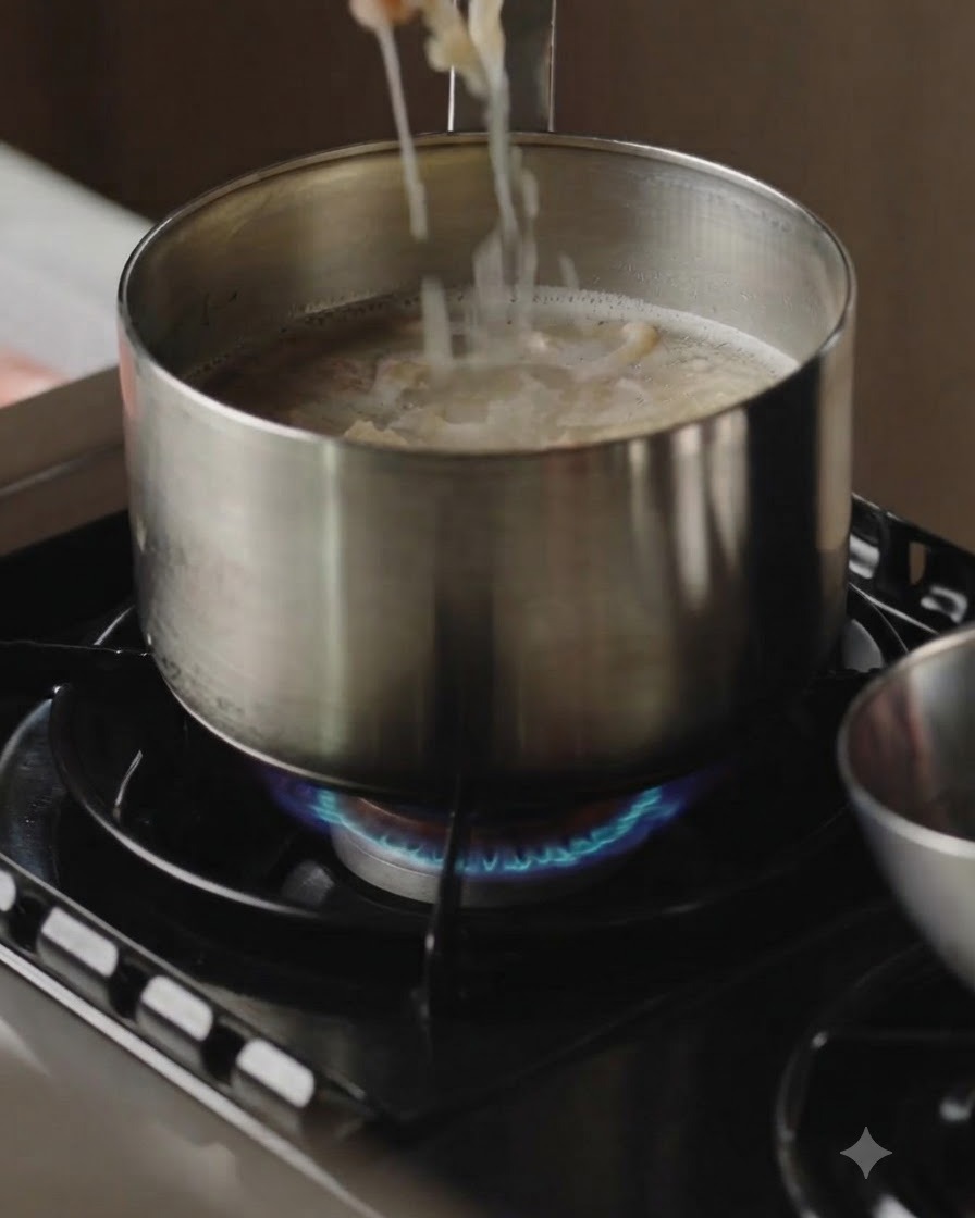 Fette di carne cotta sollevate da una pentola di brodo bollente con le bacchette.