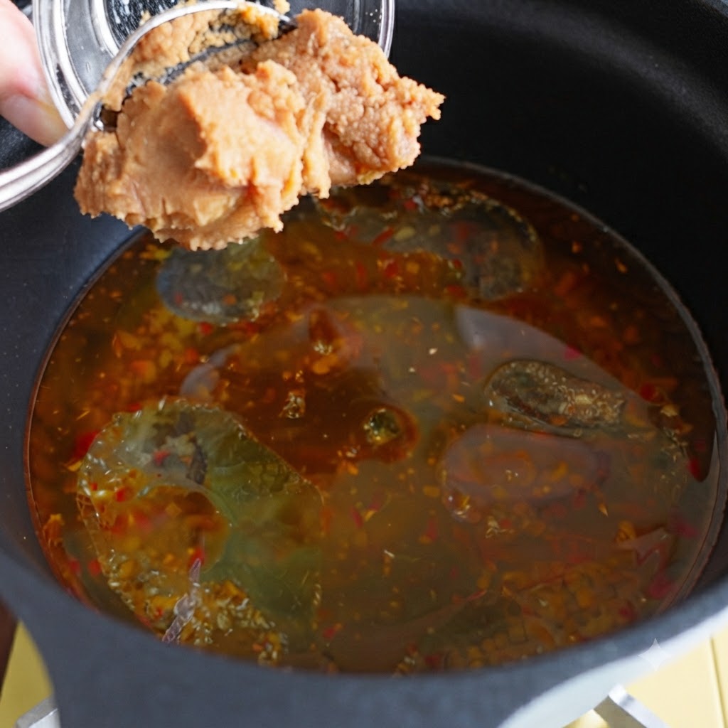 Pasta di miso aggiunta in una pentola di brodo condito.