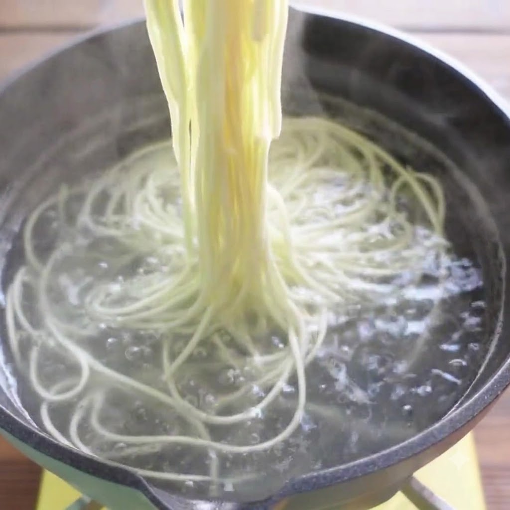 Bacchette che sollevano i noodles per ramen cotti dallacqua bollente.