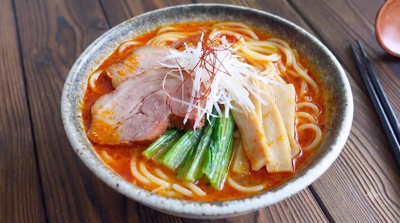 Una ciotola di ramen giapponese piccante al miso con ricco brodo rosso, tenero chashu, verdure fresche, germogli di bambù e cipollotti negi.