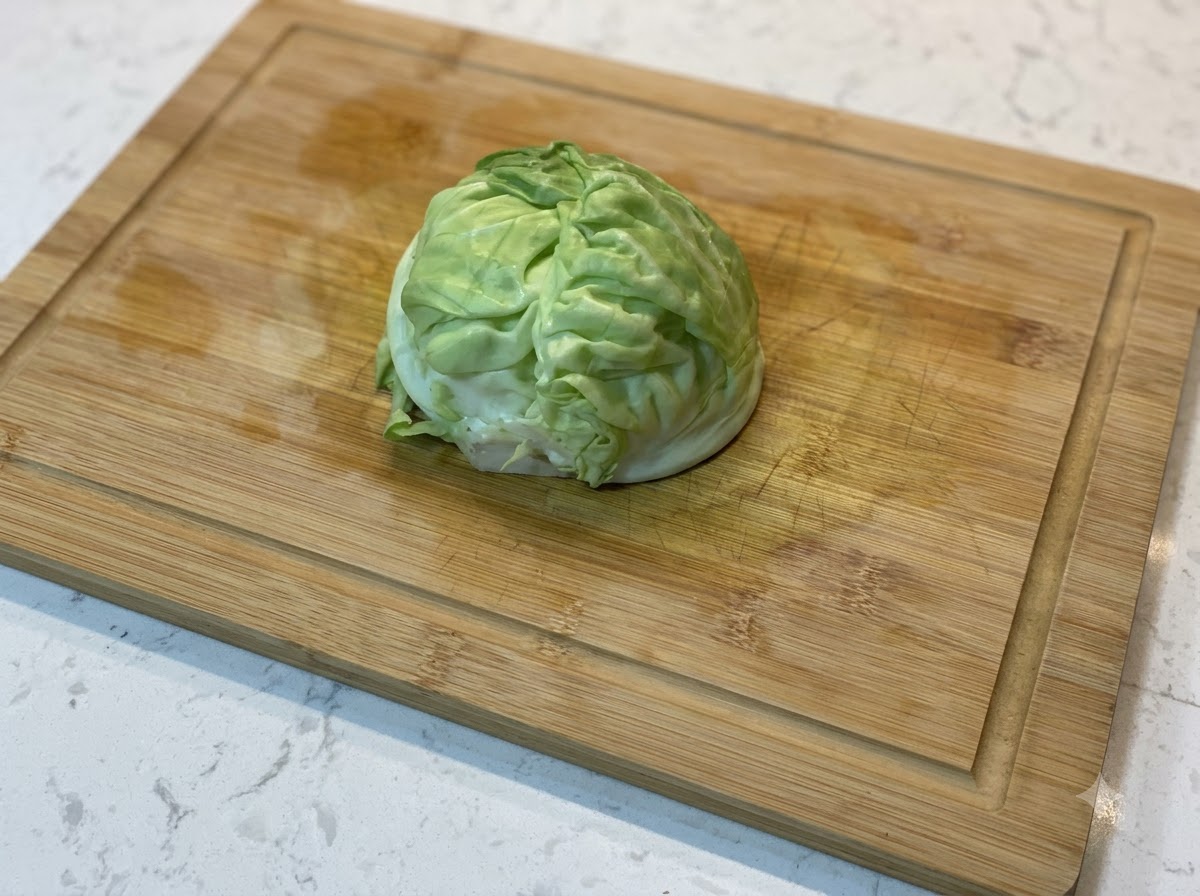 Uno spicchio di cavolo verde fresco appoggiato su un tagliere di legno.