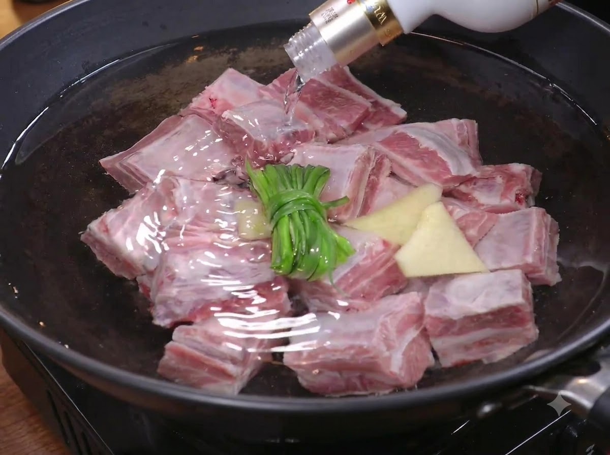 Pezzi di carne inseriti in una pentola dacqua con cipollotti e zenzero per sbollentarli.