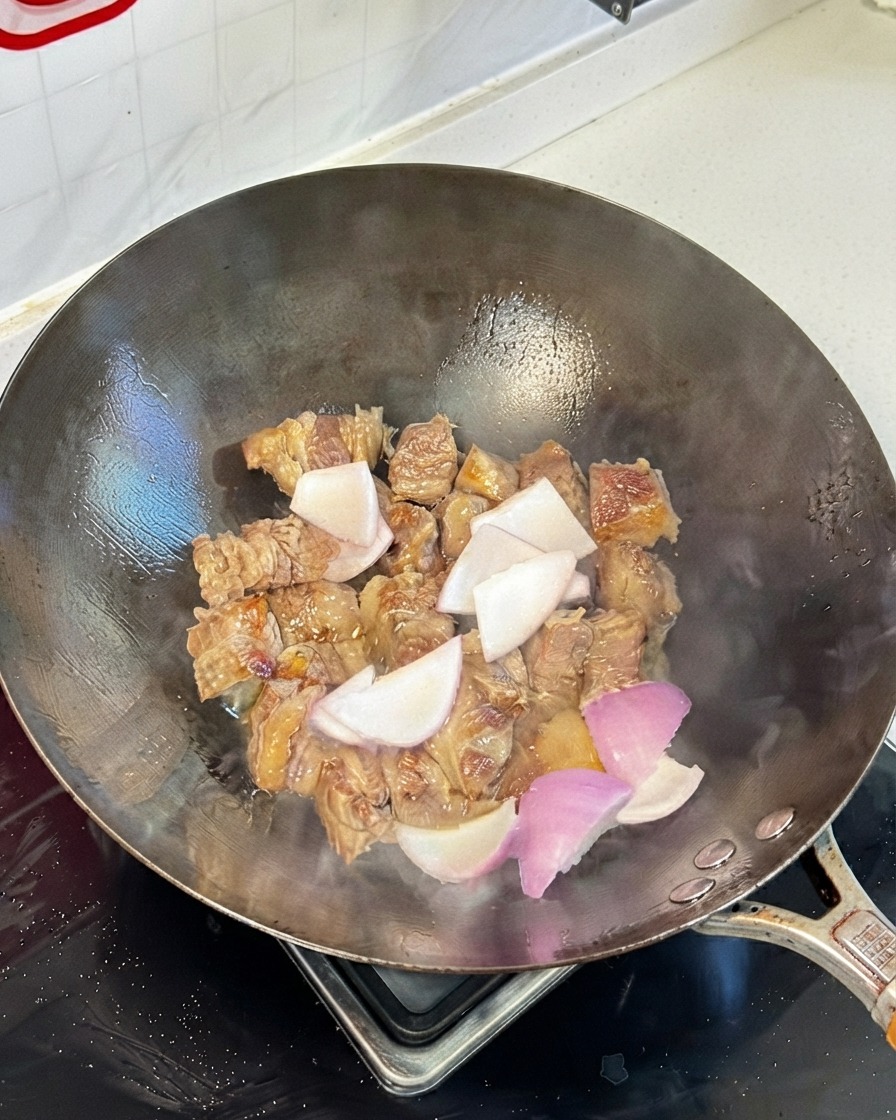 Pezzi di costolette di manzo saltati in un wok mescolati con pezzi di cipolla e salse di soia.