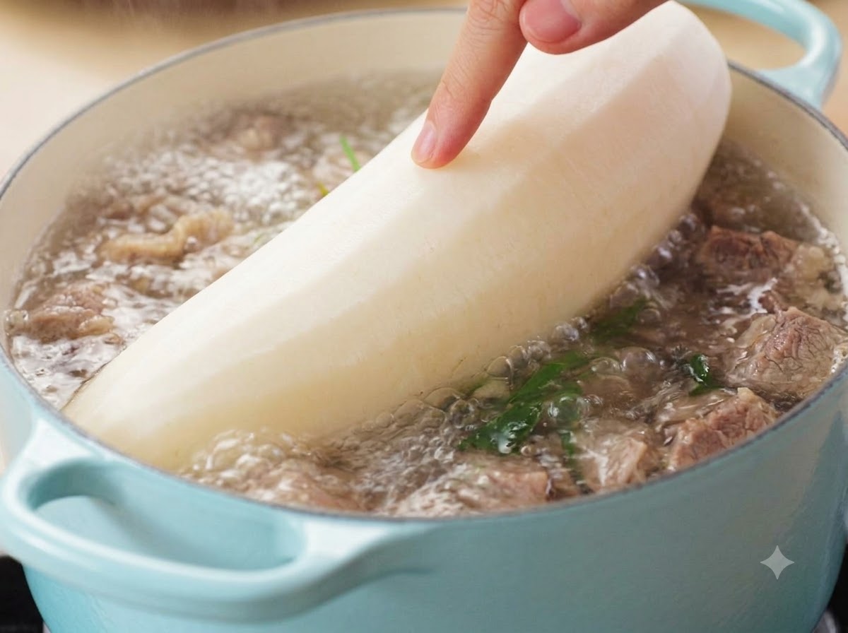Una mano che guida una grande radice bianca sbucciata in una pentola di zuppa di manzo che bolle.