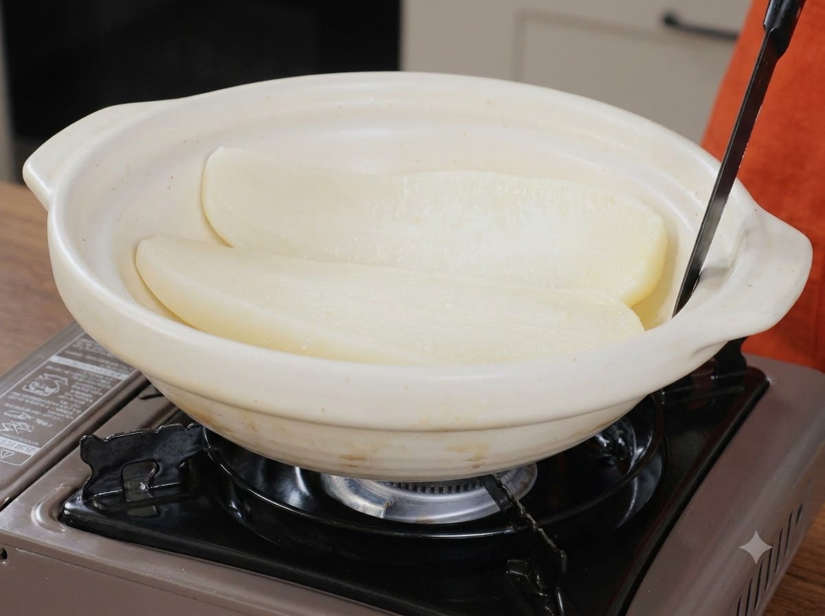 Due metà di radice bianca cotta allinterno di unampia pentola di servizio in ceramica bianca con un utensile.
