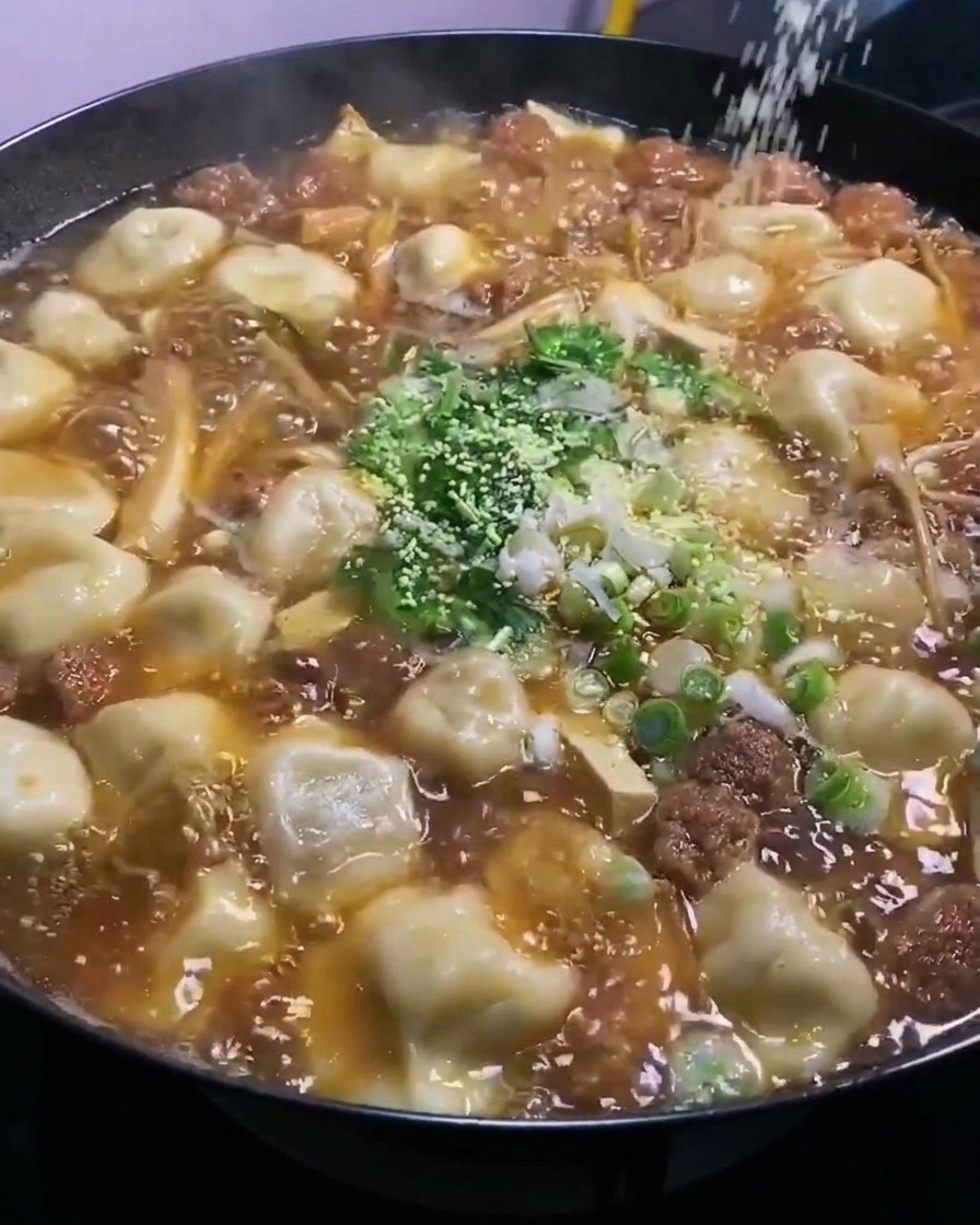 Polvere di bouillon di pollo sparsa dallalto nel wok in ebollizione.