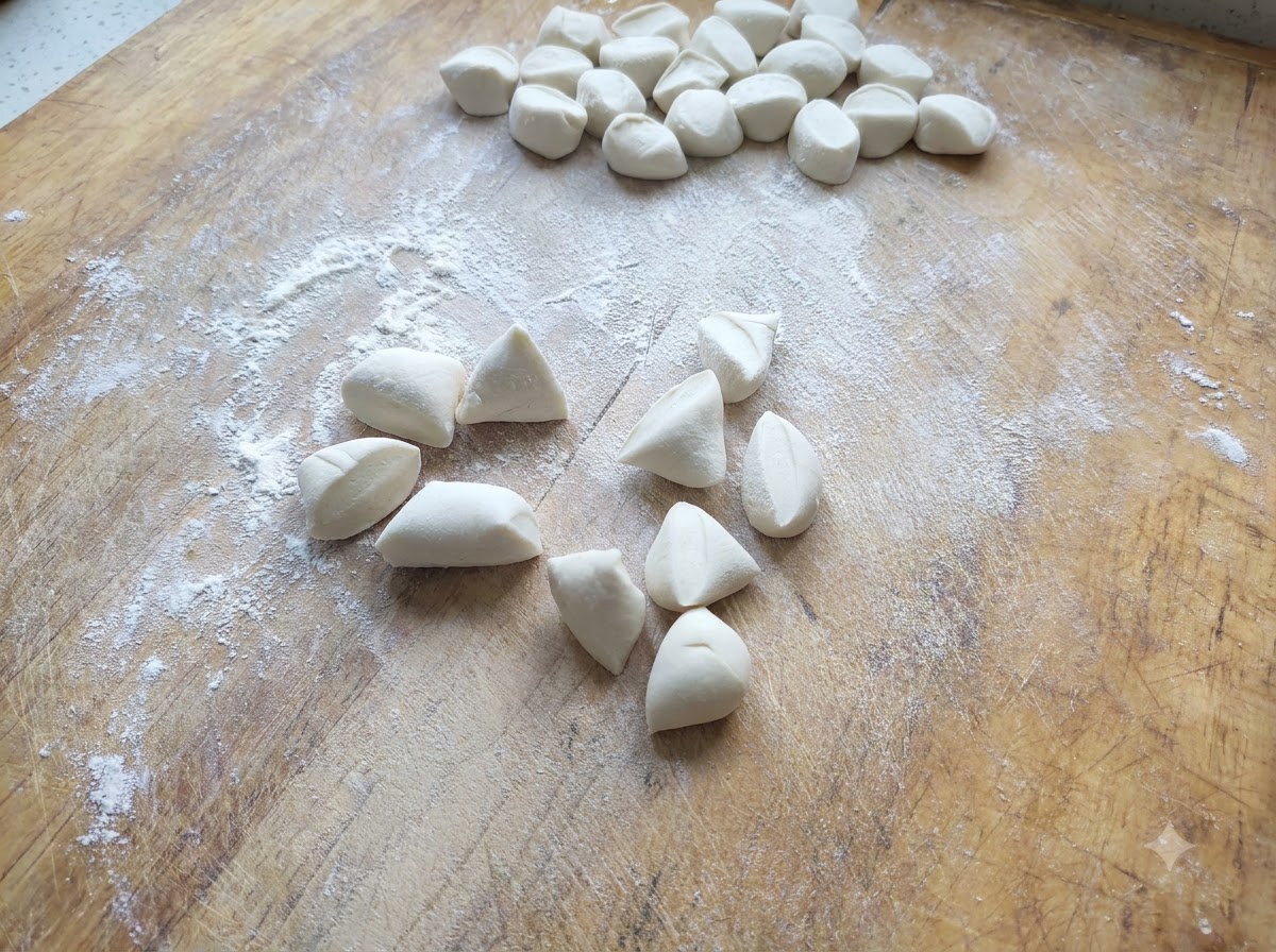 Piccoli pezzi di pasta bianca per ravioli tagliati e sparsi su un tagliere di legno infarinato.