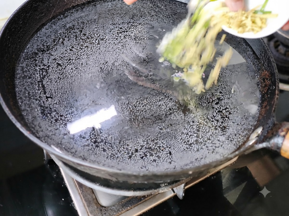 Scalogno e zenzero tritati aggiunti in un wok pieno dacqua sul fuoco.