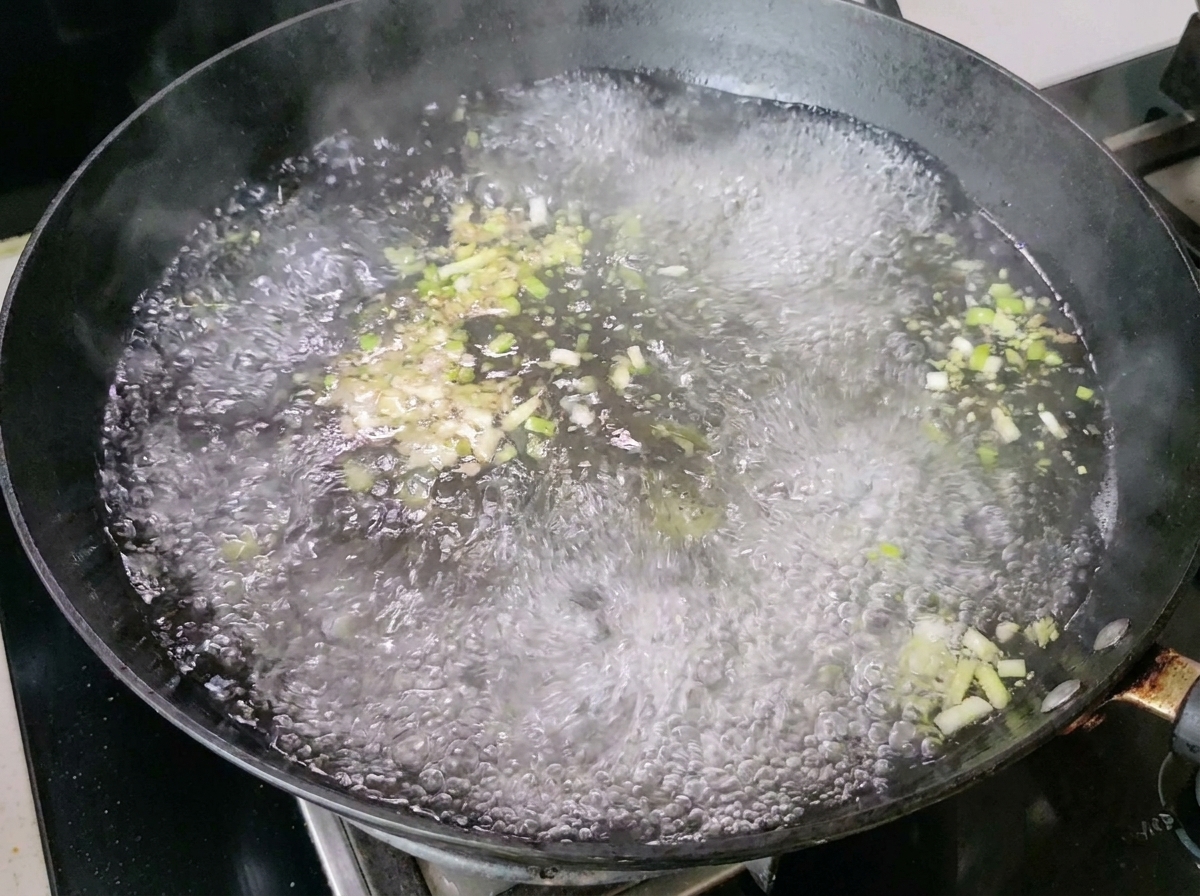 Acqua bollente con scalogno e zenzero che produce vapore nel wok.
