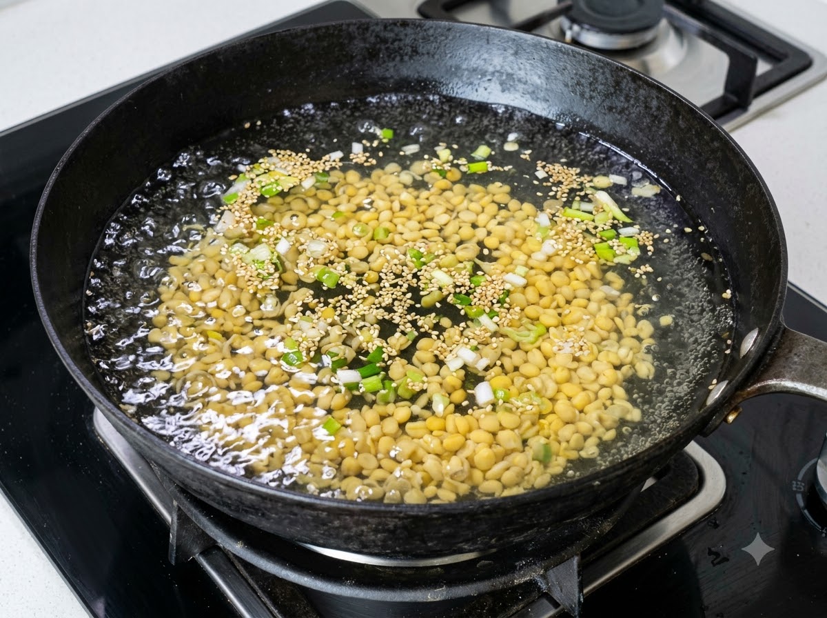 Una grande quantità di germogli di soia gialli che bollono in un wok dacqua con scalogno tritato.