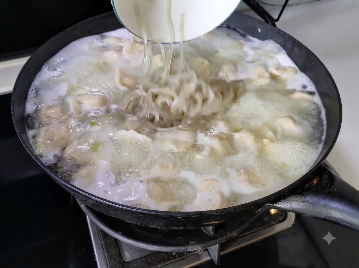 Noodles versati da una ciotola bianca nella zuppa di ravioli bollente in un wok.