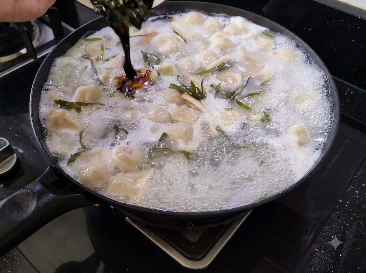 Salsa di condimento scura versata da un piccolo piatto in una grande pentola di zuppa di ravioli bollente.