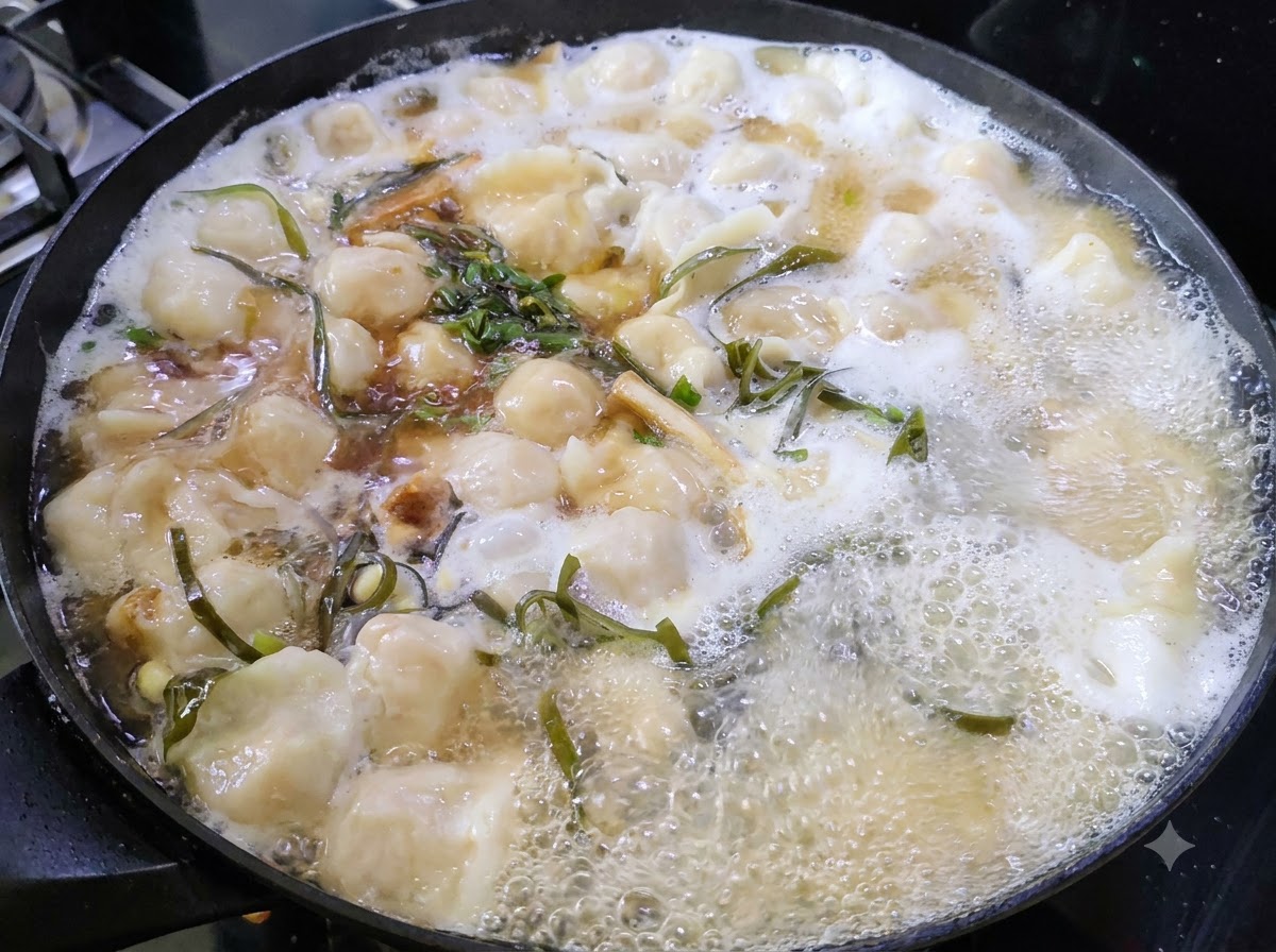 Erbe verdi tritate che galleggiano sulla superficie di una pentola di zuppa di ravioli in ebollizione.