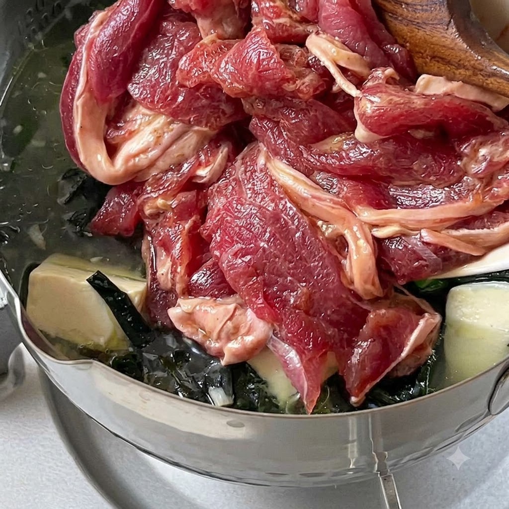 Fettine di manzo marinate fatte cadere in una pentola di zuppa in ebollizione a fuoco basso.