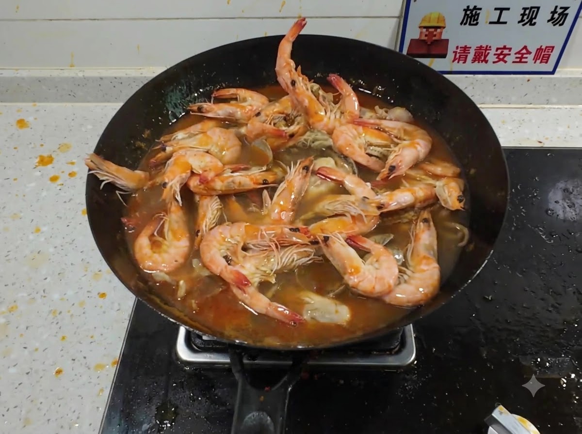 Una grande aragosta aggiunta in un wok affollato pieno di frutti di mare che sobbollono e ricco brodo rosso.