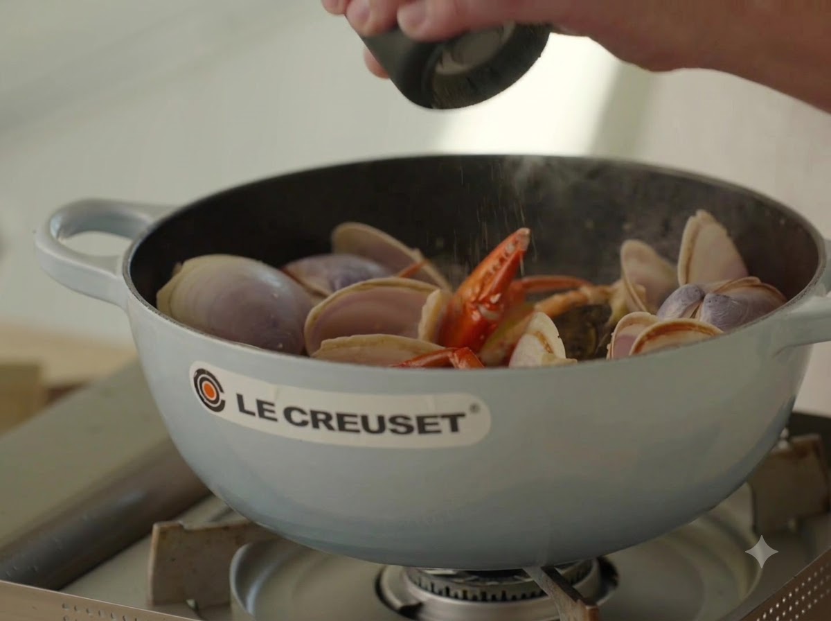 Pepe nero fresco macinato sopra il brodo di frutti di mare che bolle in una pentola.