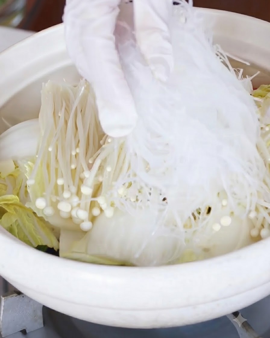Noodles di vetro messi in ammollo posizionati sopra lo strato di funghi enoki e cavolo.