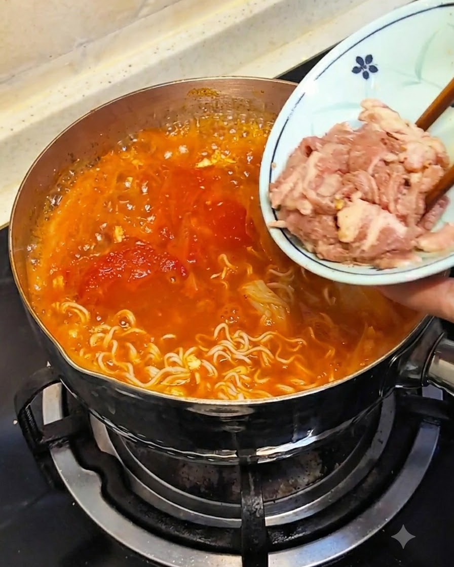 Le bacchette che immergono carne cruda tagliata sottilmente da un piccolo piatto nel brodo caldo.