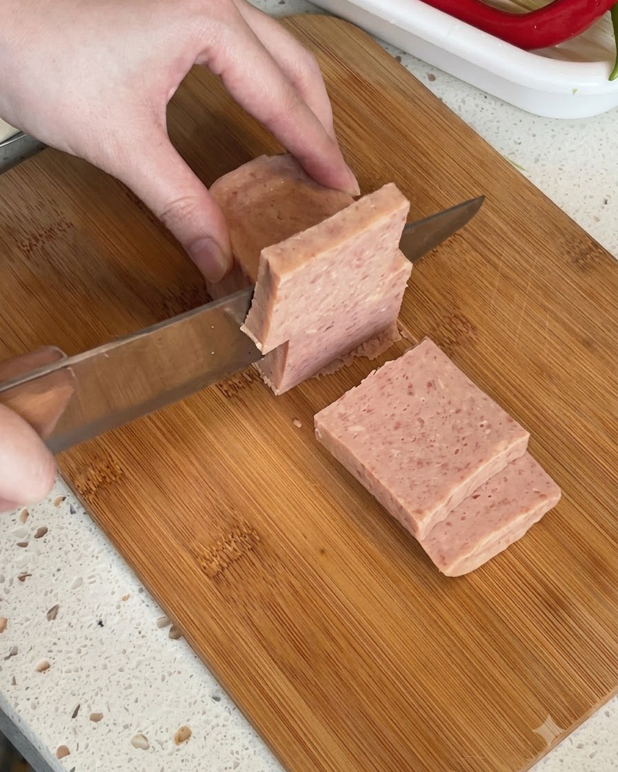 Un blocco di carne in scatola tagliato a fette spesse su un tagliere.