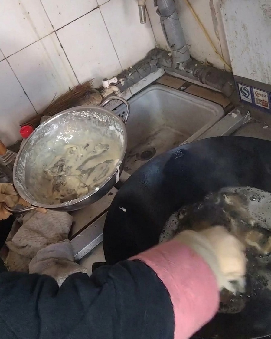 Frittura di strisce di funghi rivestite in un wok pieno di olio caldo.
