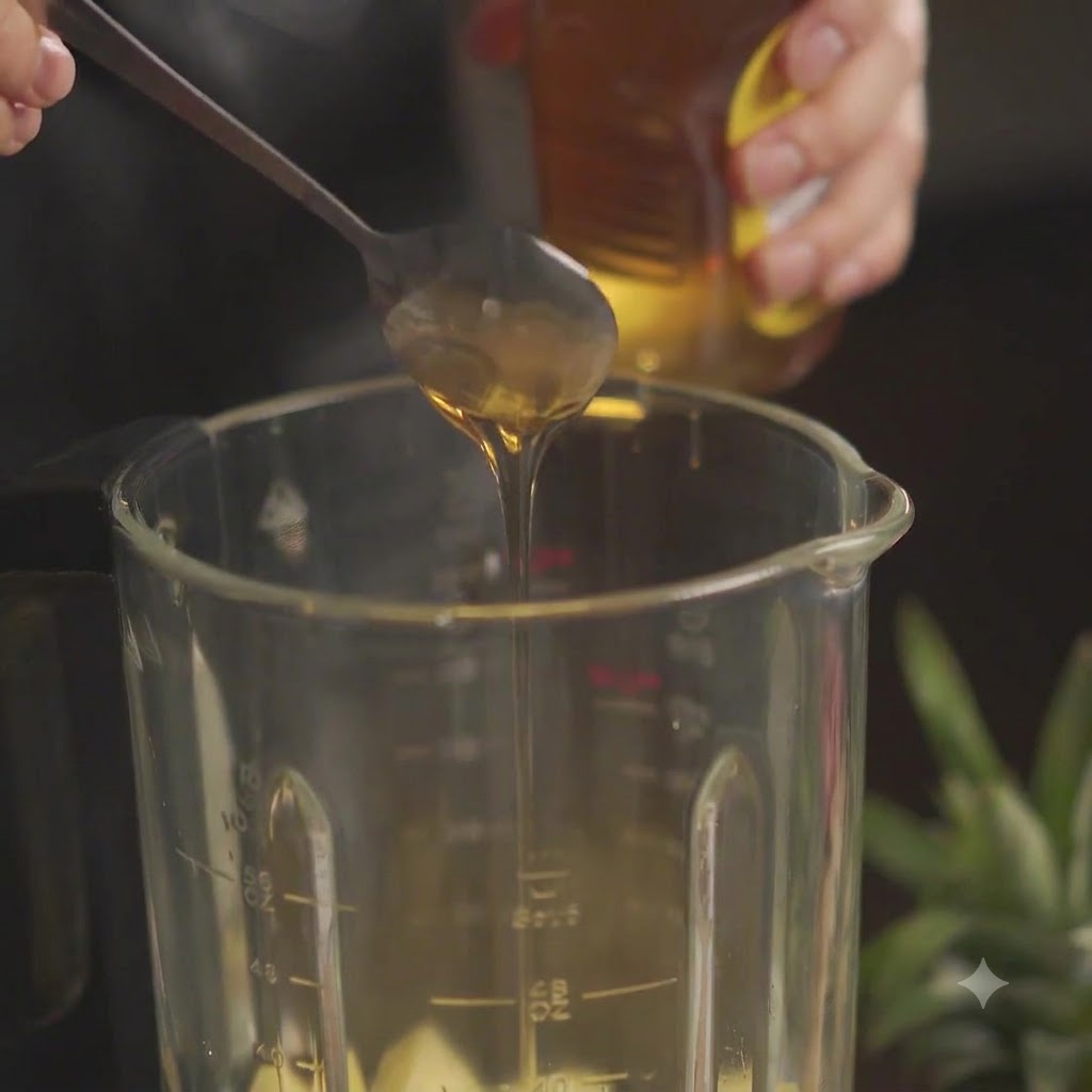 Un cucchiaio di miele aggiunto in un barattolo del frullatore riempito di ananas tritato.