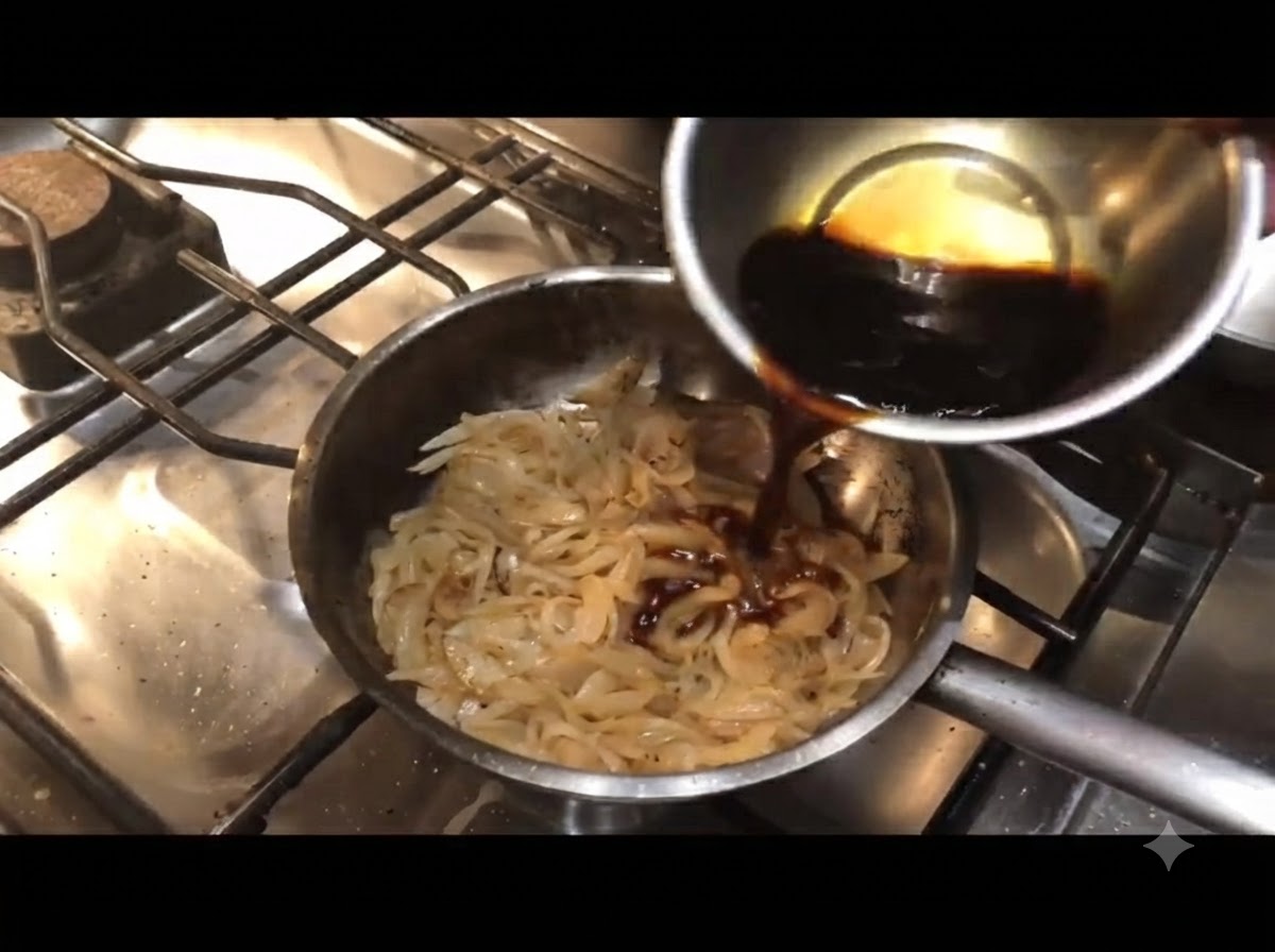 Salsa scura versata da una ciotolina in una padella di cipolle cotte.