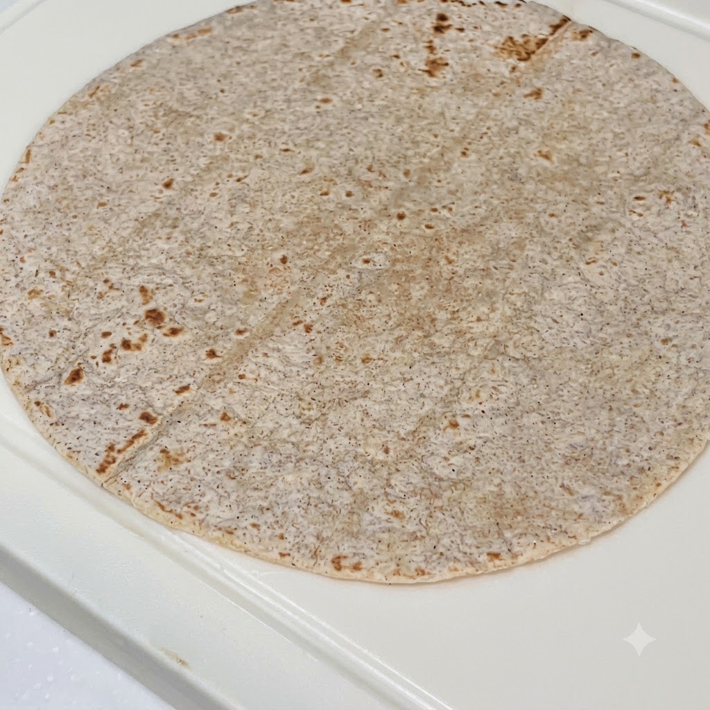 Una tortilla integrale farcita con salsa al burro darachidi, pollo a fette, cavolo rosso e lattuga fresca.